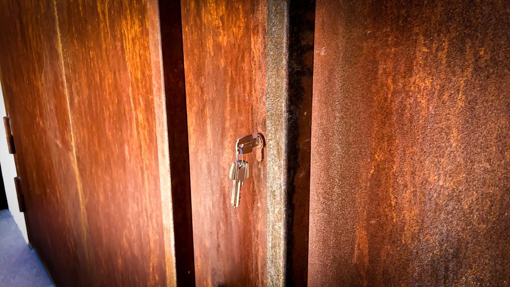 Detalle de la textura oxidada de una puerta de acero corten con su cerradura