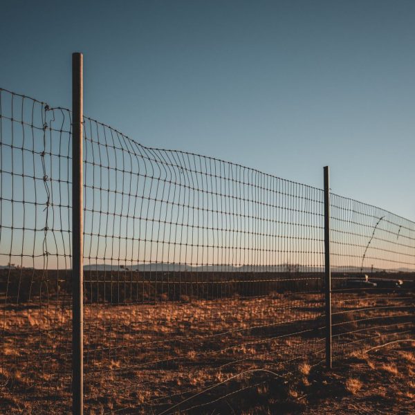 Cerramiento de malla ganadera con postes en una finca