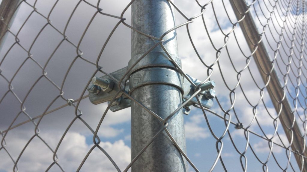 Malla de simple torsión galvanizada sujeta a un poste con abrazaderas
