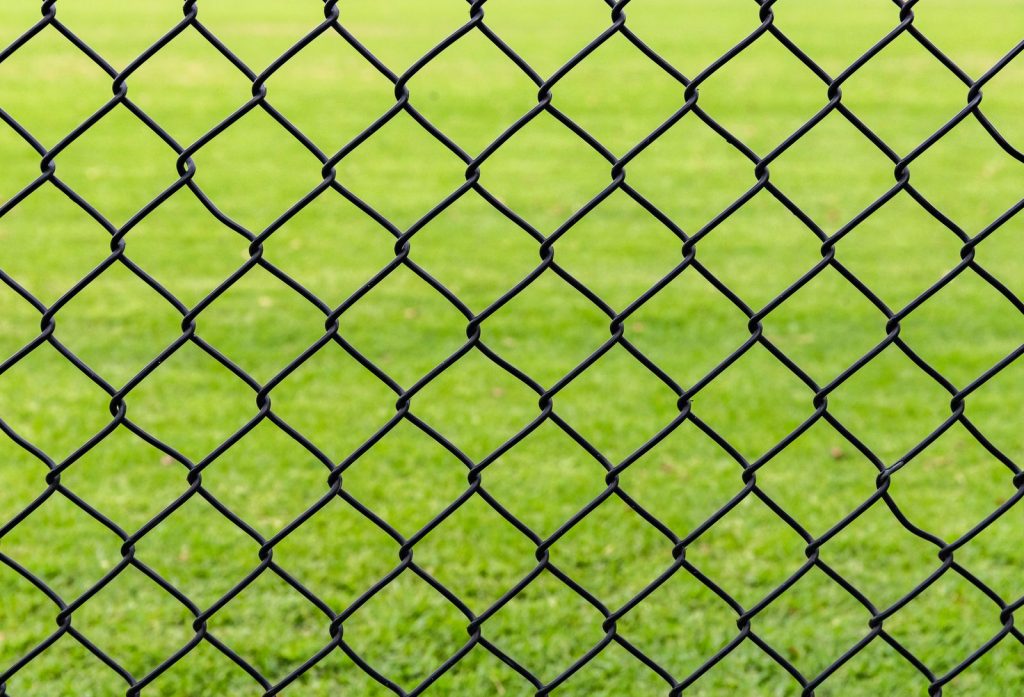 Malla de simple torsión plastificada verde delante de césped